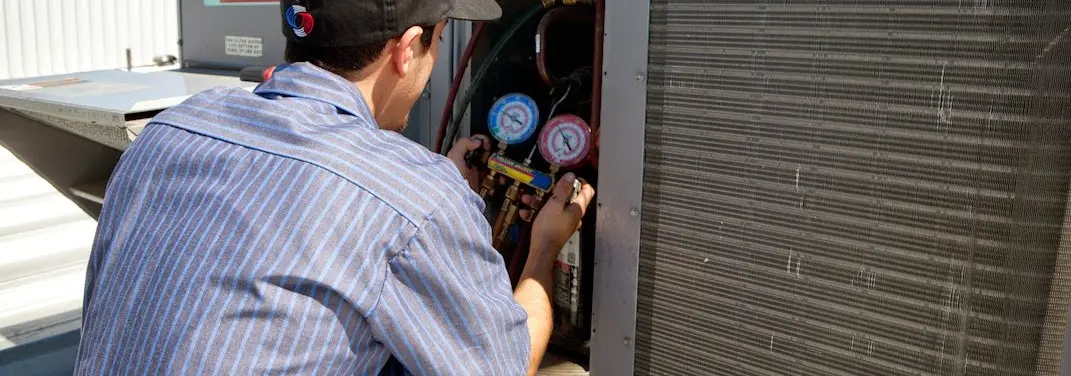 HVAC technician servicing a condenser unit in El Granada