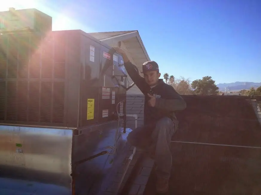 HVAC technician performing Air Duct Cleaning on a rooftop unit in El Granada